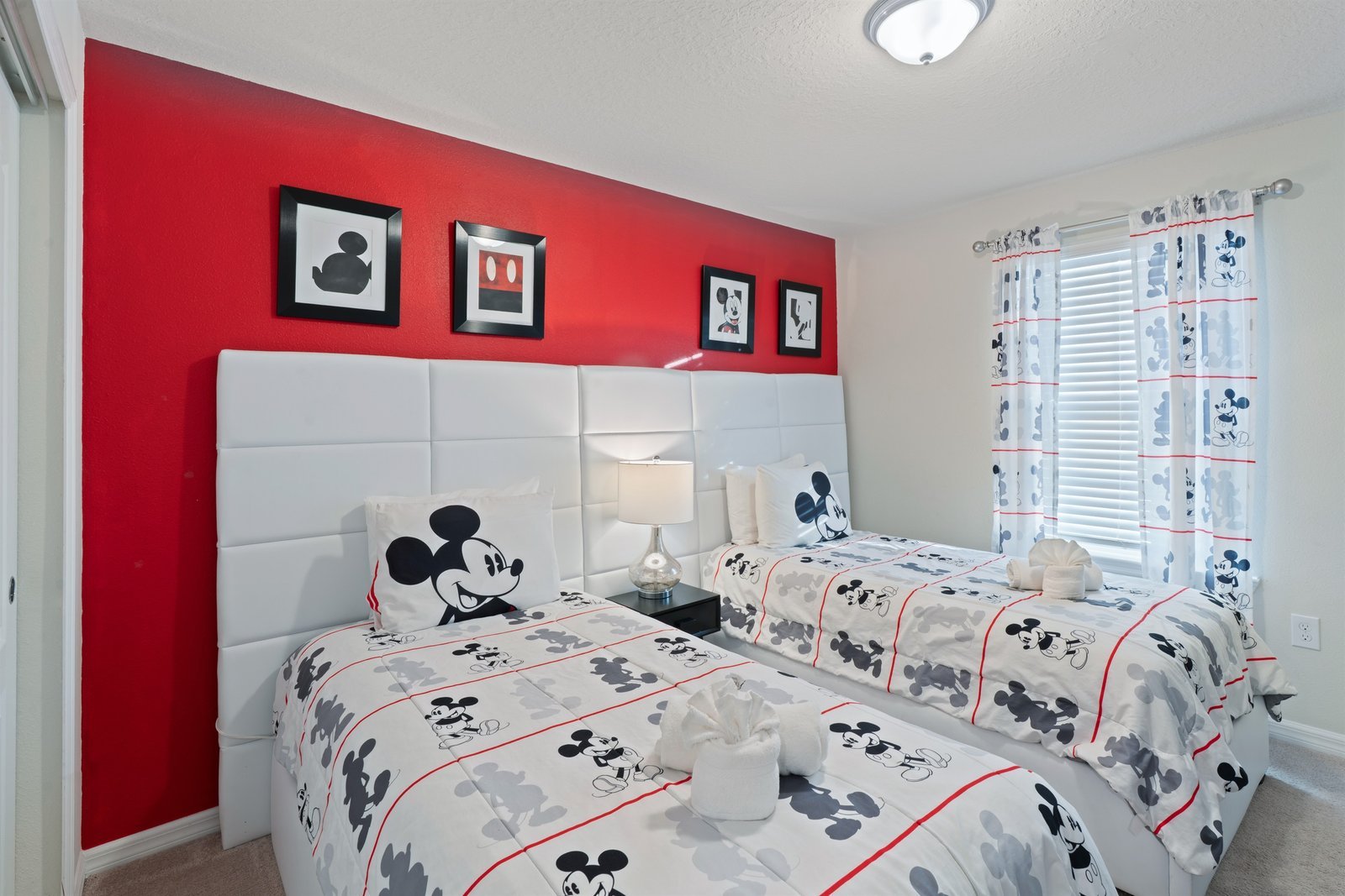 Mickey themed kids room with two twin beds, smart TV, storage chest, and closet